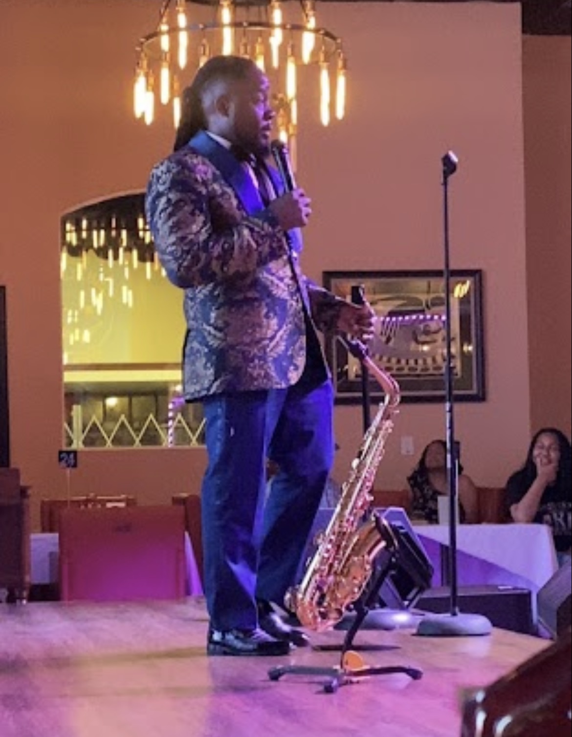 Dr. Demoine Kinney performing live on stage with saxophone